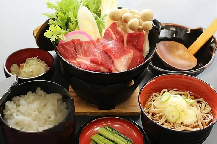 Ein traditionelles japanisches Gericht mit rohem Fleisch, Pilzen, Reis und Soba-Nudeln.